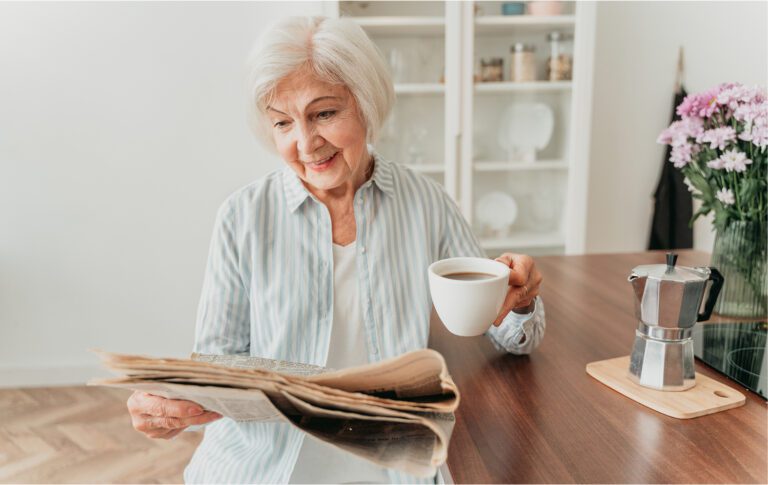 Vrouw met koffie in de hand die de krant leest